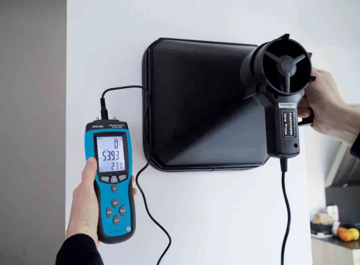 Technicien utilisant un anémomètre à cône sur une bouche d'extraction